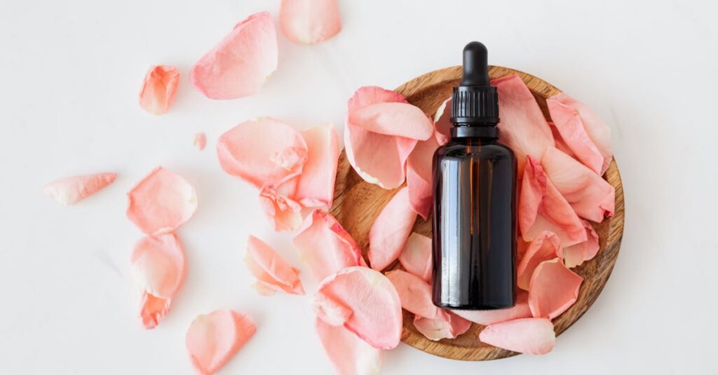 top view of empty brown bottle for skin care product placed on wooden plate with fresh pink rose pet